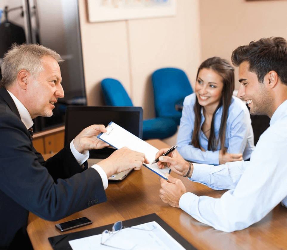 A man handing over papers to two people.